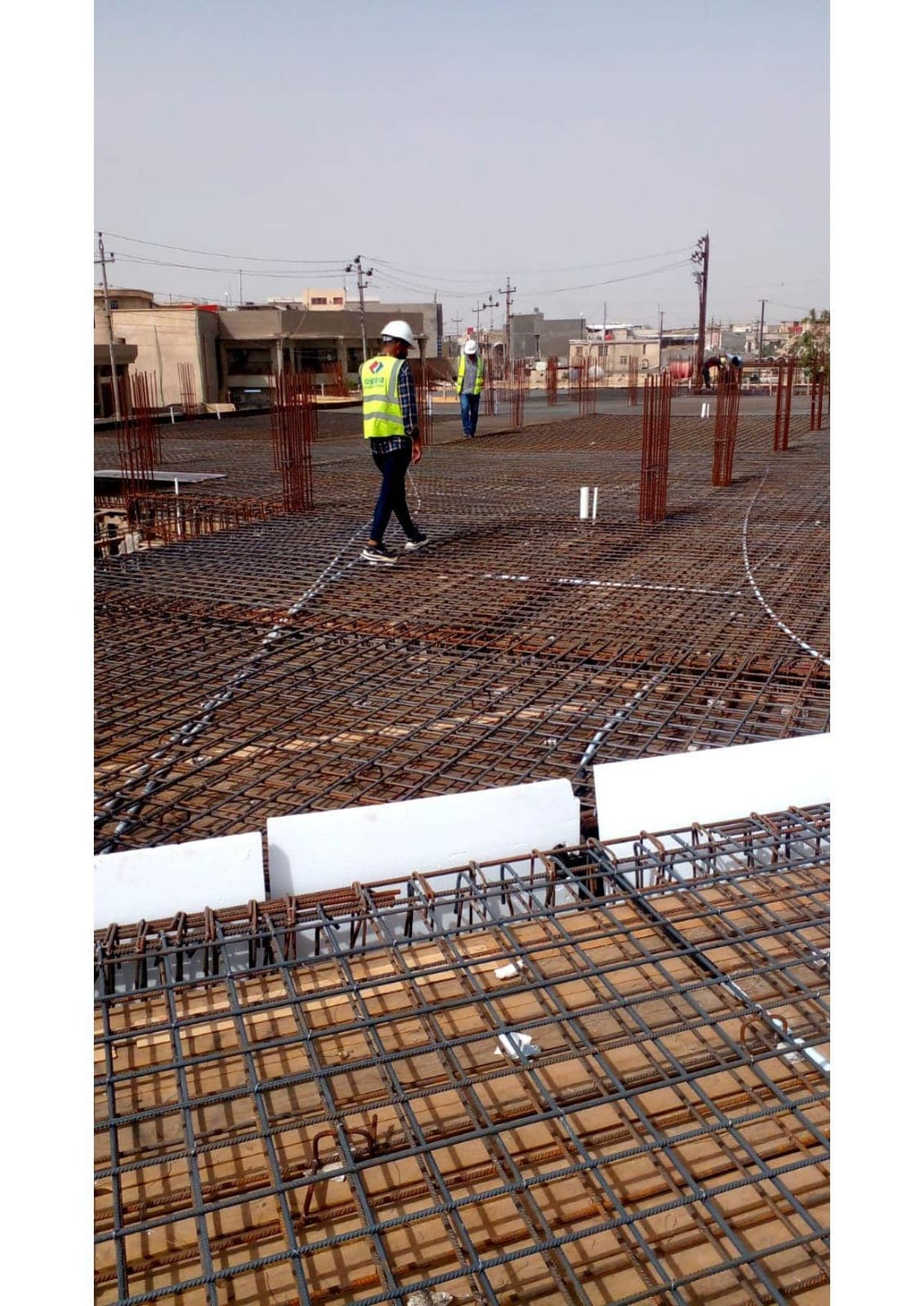 Two engineers inspecting the foundation reinforcement mat before the pour