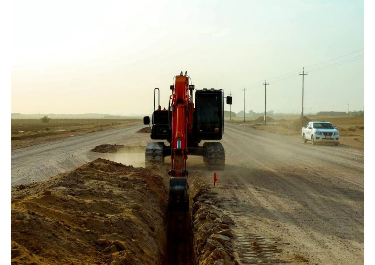 حفارة تحفر خندق تمديدات مستقيماً على طول ممر الطريق الجديد